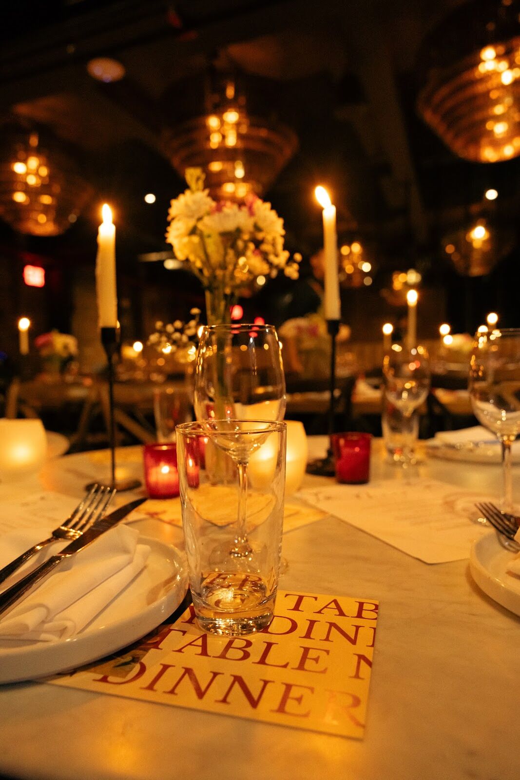 A candlelit table set with flowers and a Dinner Table menu card